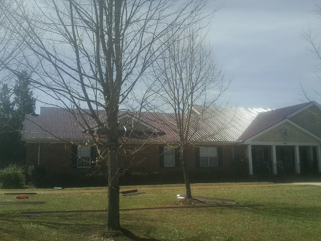 Red metal roof on a brick building seen from the front lawn in Middletown