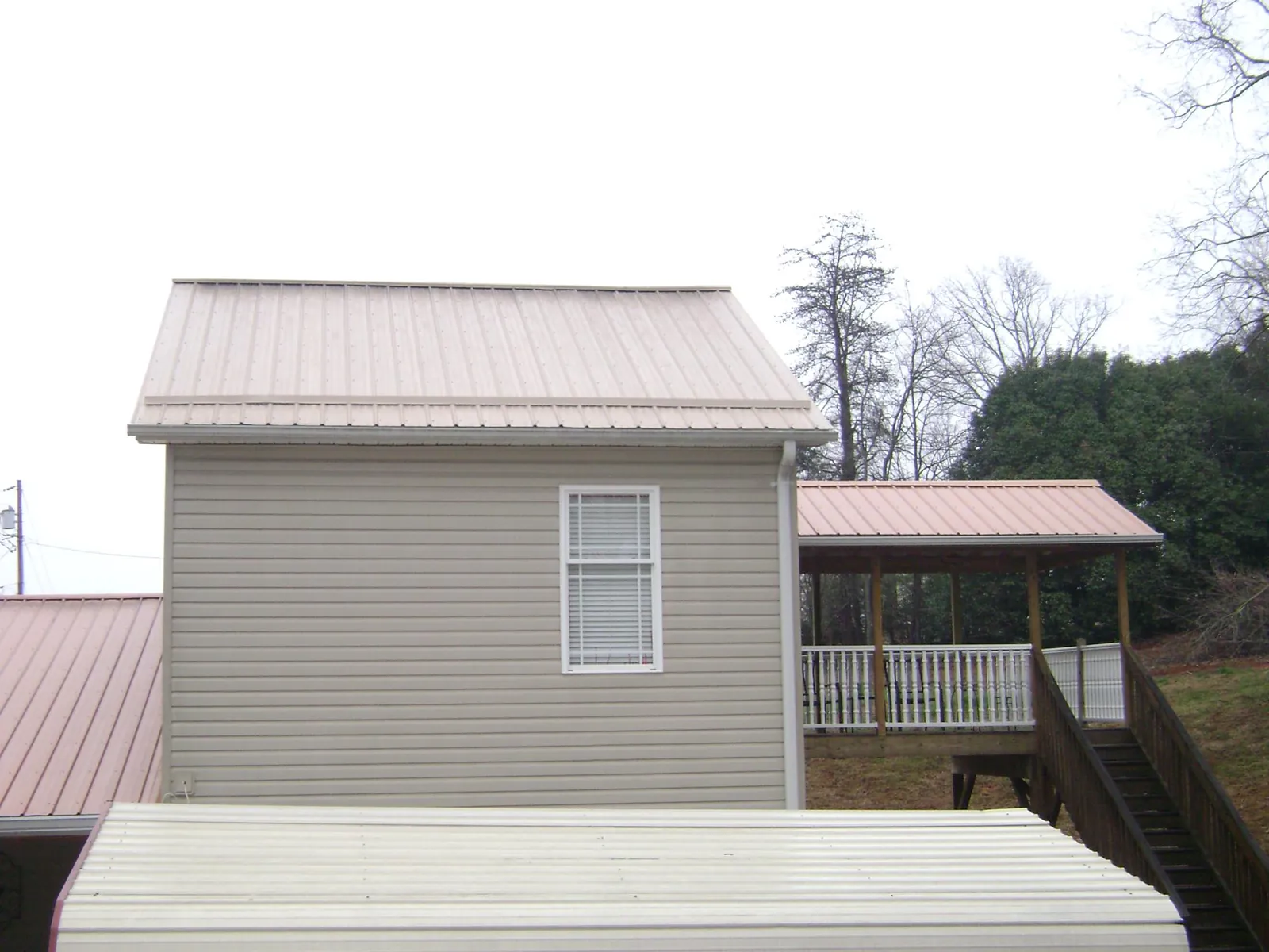 Tan metal roofs on a two story addition and attached porch, from a Roof Replacement job in Middletown